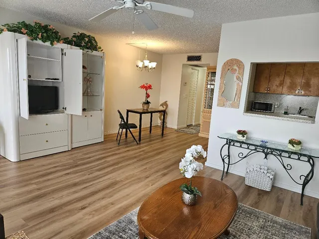 a living room with furniture a flat screen tv and kitchen view