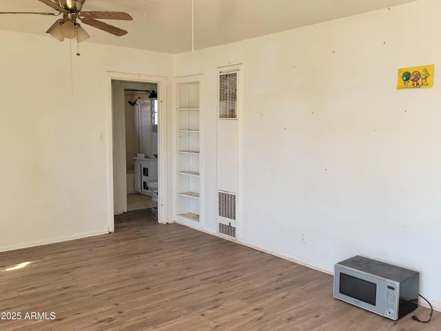 an empty room with wooden floor closet and windows