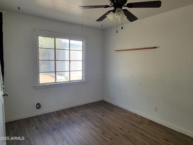 an empty room with a window and a ceiling fan
