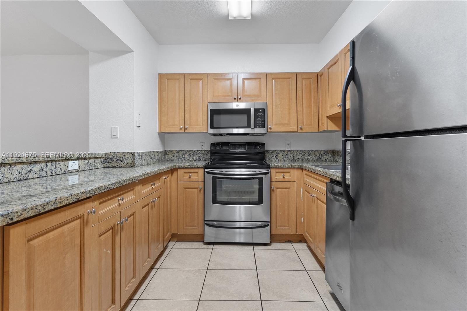 5102 Northwest 79th Avenue, Unit 304 Doral, FL 33166 - Photo 2 of 25 a kitchen with granite countertop a refrigerator and a sink