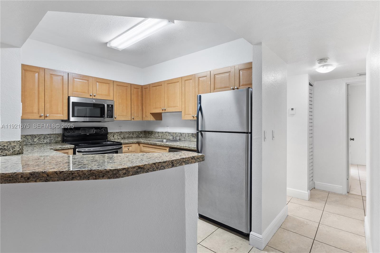 5102 Northwest 79th Avenue, Unit 304 Doral, FL 33166 - Photo 9 of 25 a kitchen with a refrigerator a microwave a stove and cabinets