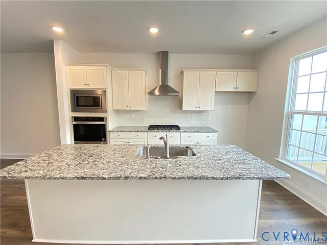 a kitchen with kitchen island granite countertop a stove a sink and a refrigerator