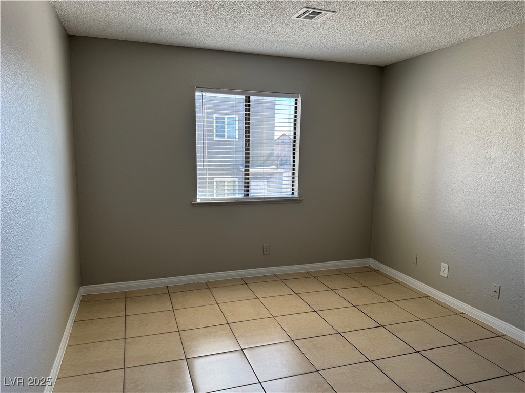 6925 Hopkins Drive, Unit 4 Las Vegas, NV 89156 - Photo 11 of 12 Spare room featuring a textured wall, light tile patterned floors, and a textured ceiling