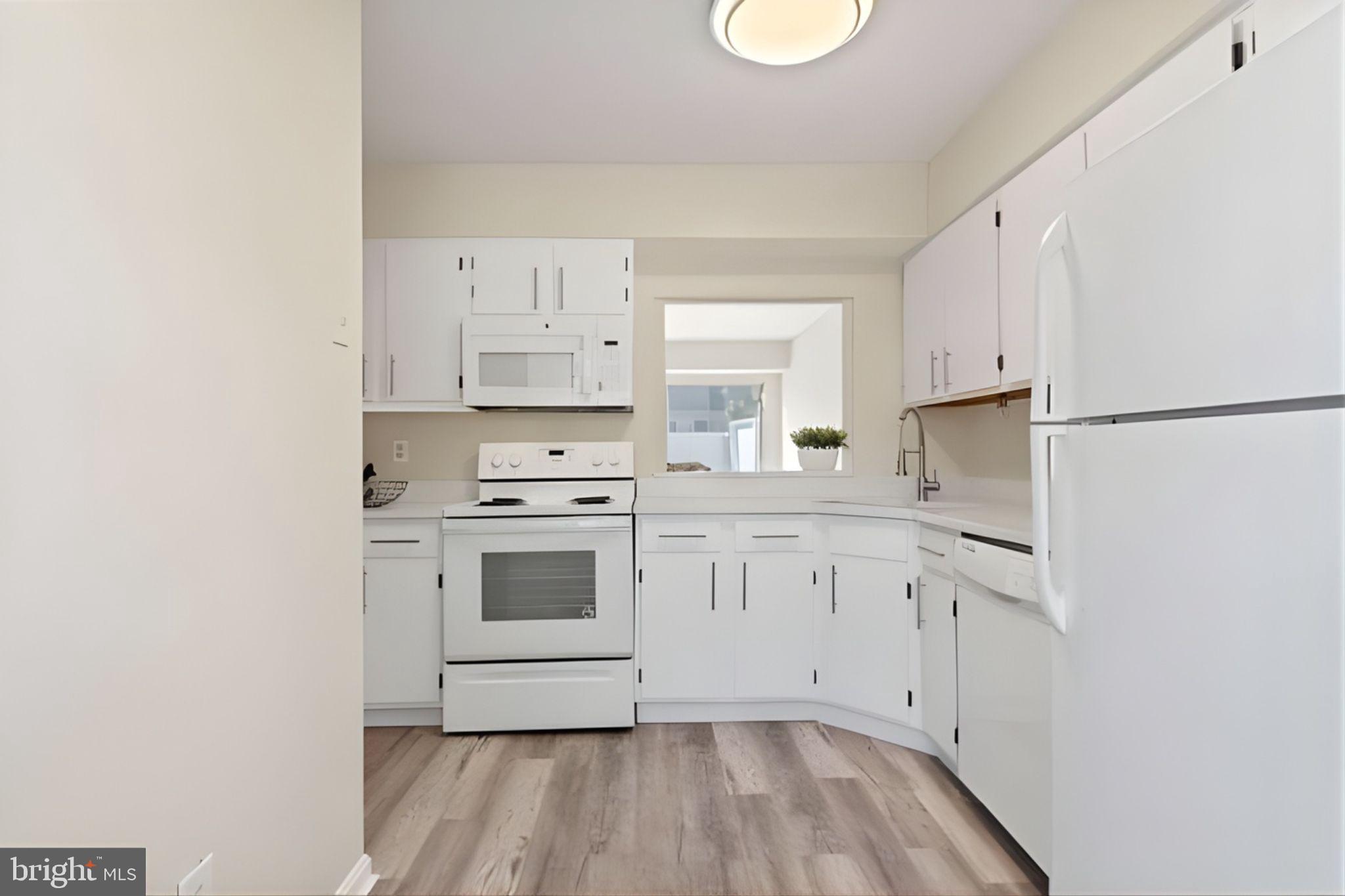 107 St Charles Square Sterling, VA 20164 - Photo 4 of 27 a kitchen with white cabinets and white appliances
