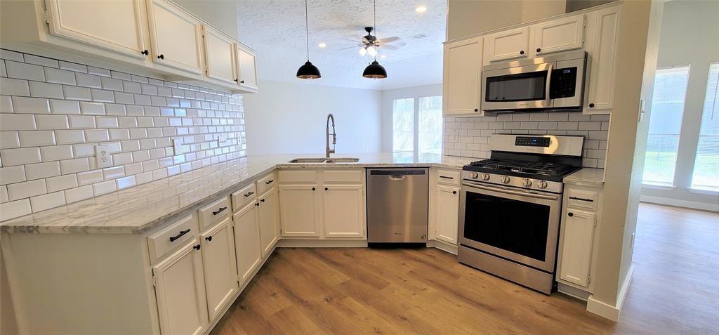 a kitchen with stainless steel appliances white cabinets a stove top oven a sink and dishwasher