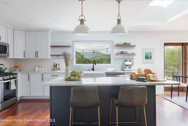 a kitchen with stainless steel appliances a dining table chairs and white cabinets