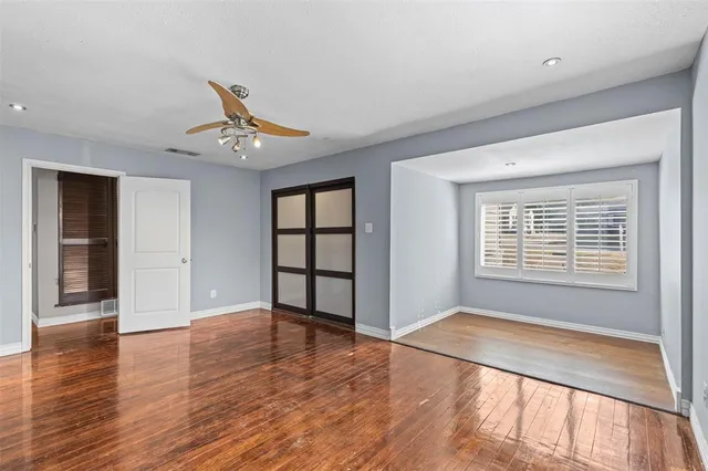 a view of an empty room with a window and wooden floor