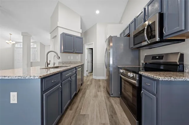 a kitchen with granite countertop a refrigerator a sink dishwasher and a stove with wooden floor