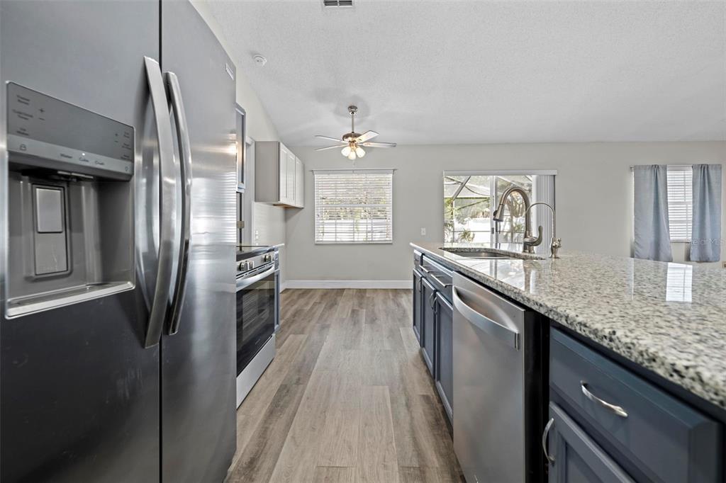 8155 Giffen Lane Spring Hill, FL 34608 - Photo 17 of 52 a kitchen with granite countertop a refrigerator a sink dishwasher and a stove with wooden floor