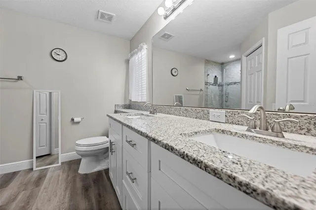 a bathroom with a granite countertop sink a toilet and a mirror