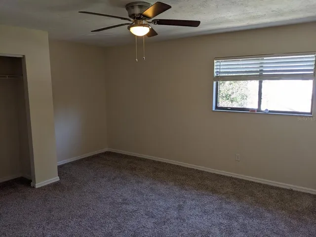 an empty room with windows and fan
