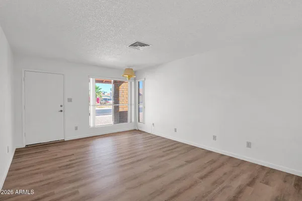 an empty room with wooden floor and windows