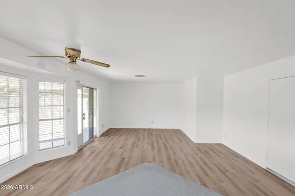 an empty room with wooden floor fan and windows