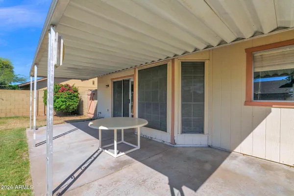 a patio with table and chairs and potted plants