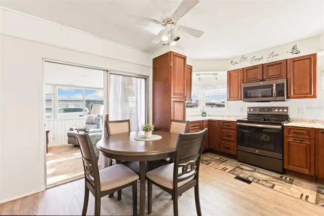 a dining room with stainless steel appliances a dining table wooden floor and a kitchen view