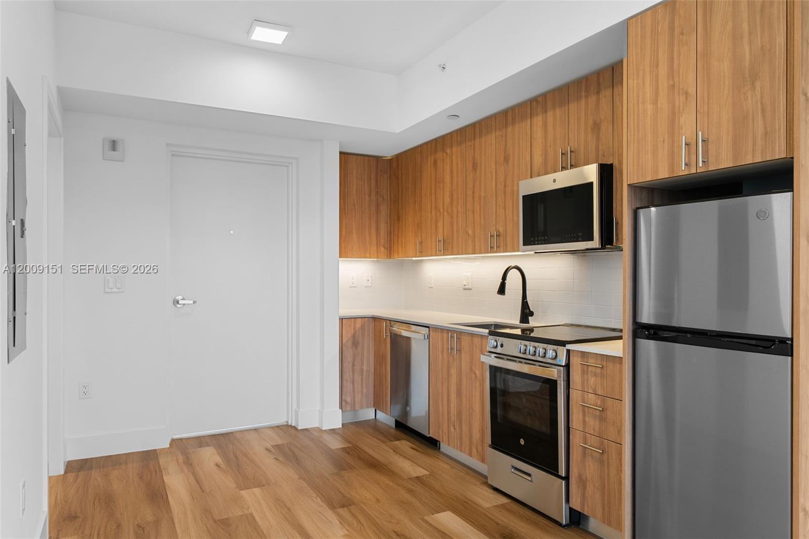 650 Southwest 1st Street, Unit 402 Miami, FL 33130 - Photo 9 of 16 a view of a kitchen with a sink a refrigerator a microwave and cabinets