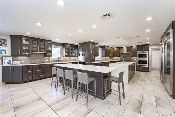 a kitchen with stainless steel appliances kitchen island granite countertop a sink a stove a dining table and chairs