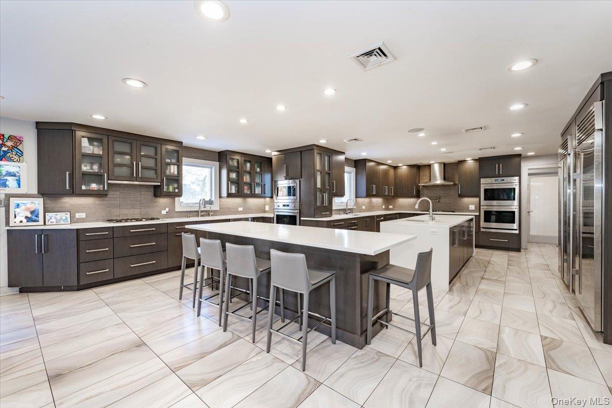 22 Larch Hill Road Lawrence, NY 11559 - Photo 5 of 31 a kitchen with stainless steel appliances kitchen island granite countertop a sink a stove a dining table and chairs