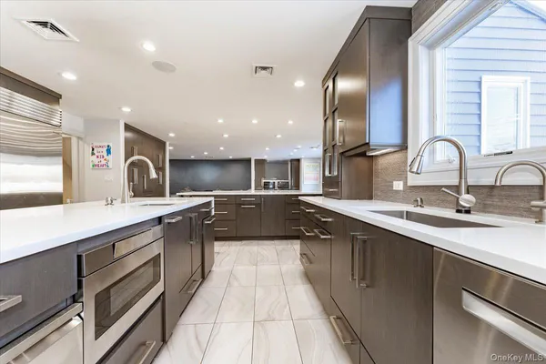 a large kitchen with a large counter top a sink and stainless steel appliances