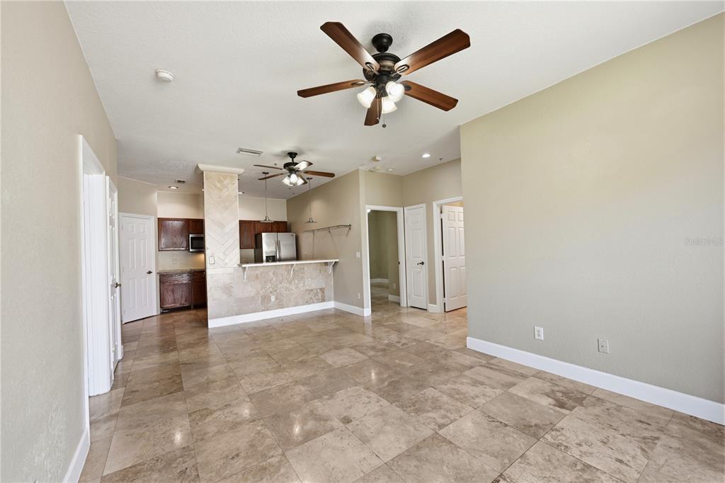 580 Brantley Terrace Way, Unit 104 Altamonte Springs, FL 32714 - Photo 5 of 32 an empty room with a kitchen and a ceiling fan
