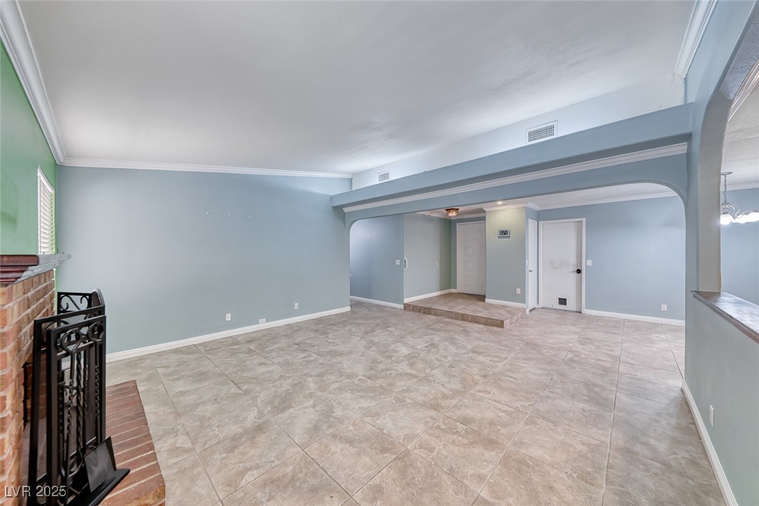 632 Arrayo Way Boulder City, NV 89005 - Photo 16 of 40 Unfurnished living room featuring arched walkways, ornamental molding, a fireplace, and baseboards