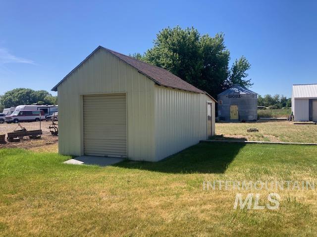 1095 County Road 70 Weiser, ID 83672 - Photo 34 of 44 Metal outbuilding with a single garage door and a side entry door, featuring a pitched shingle roof