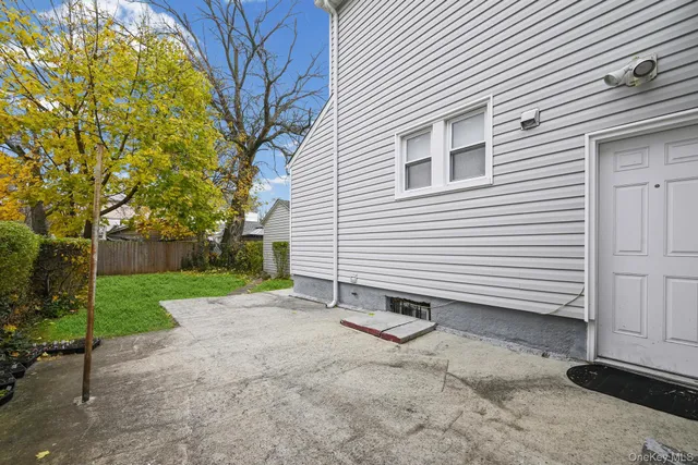 a view of a white house with a yard and table and chair under an umbrella