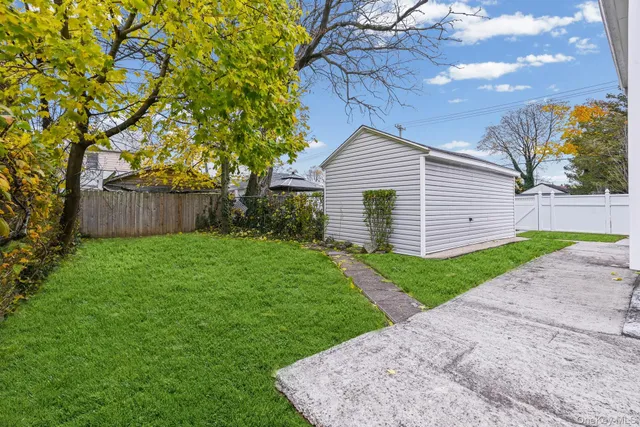 a view of a house with a small yard and a large tree