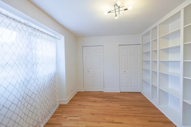 a view of an empty room with wooden floor and closet