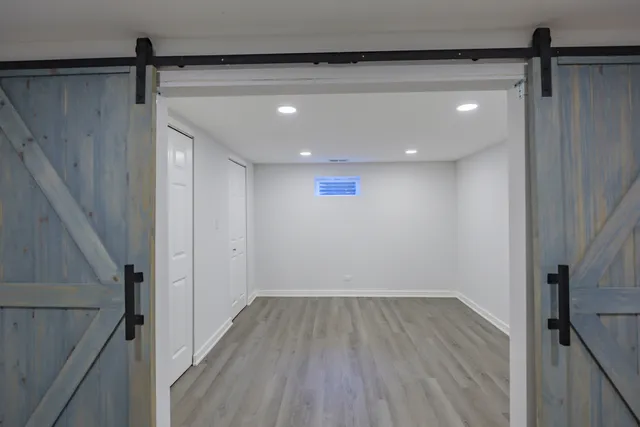 a view of an empty room with wooden floor and a kitchen