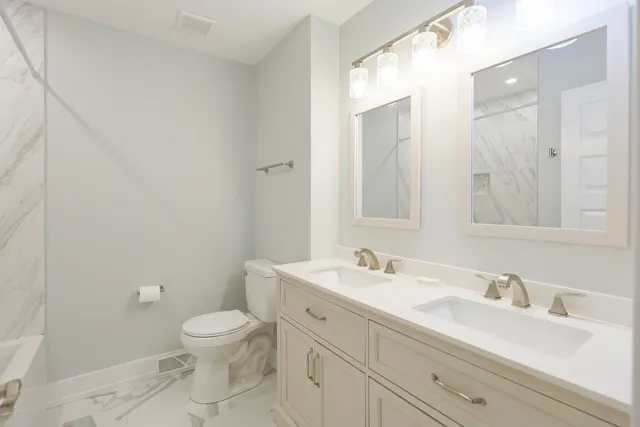 a bathroom with a toilet a sink a mirror and vanity