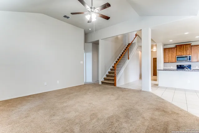 a view of a livingroom with a ceiling fan and staircase