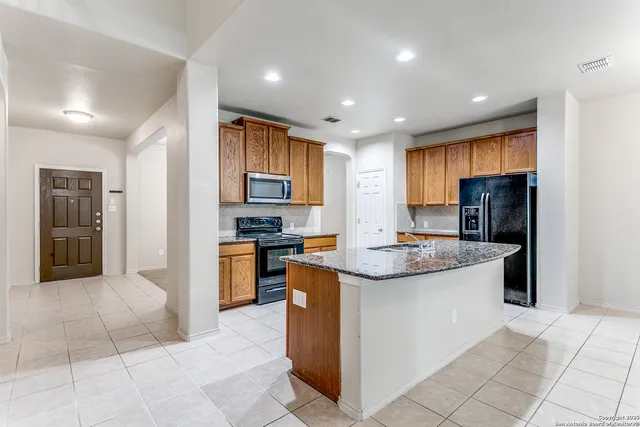 a kitchen with stainless steel appliances granite countertop a refrigerator and a sink
