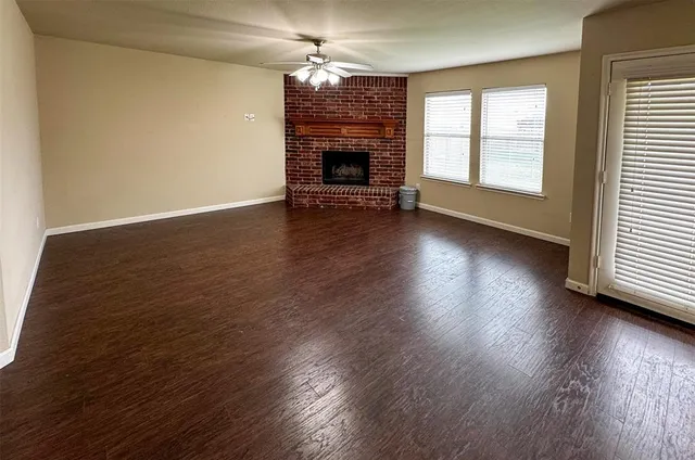 an empty room with wooden floor fireplace and windows