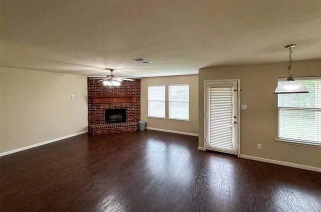 an empty room with wooden floor fireplace and windows