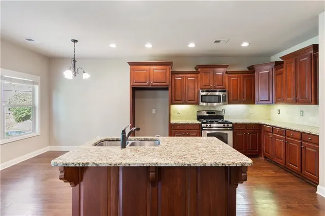 a kitchen with granite countertop kitchen island stainless steel appliances a sink stove and cabinets