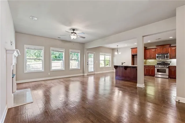 a view of an empty room with wooden floor and a kitchen