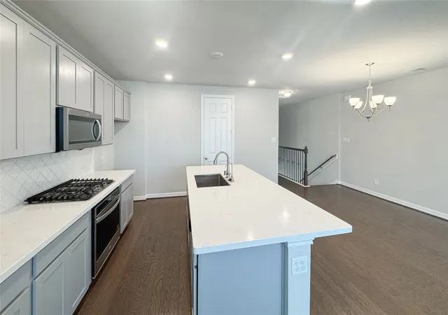 a kitchen with kitchen island a sink dishwasher stove and oven with wooden floor