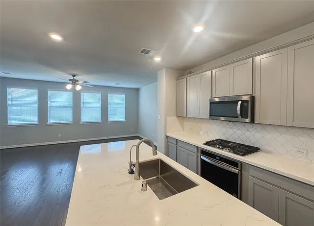 a kitchen with stainless steel appliances kitchen island granite countertop a stove and a sink