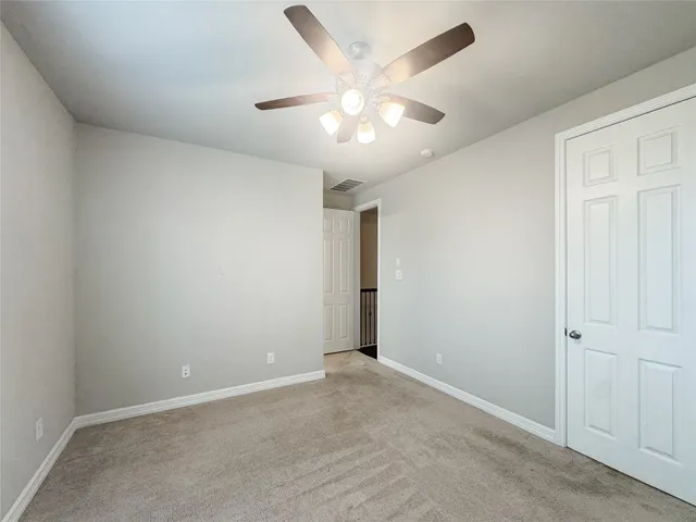 an empty room with a chandelier fan and closet area