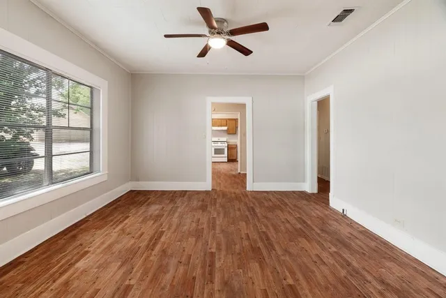 a view of empty room with wooden floor and fan