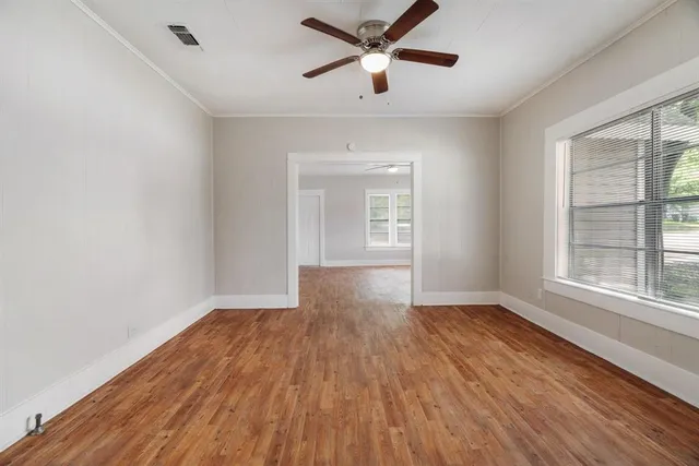 a view of empty room with wooden floor and fan