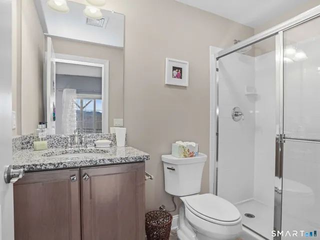 a bathroom with a granite countertop sink toilet and shower