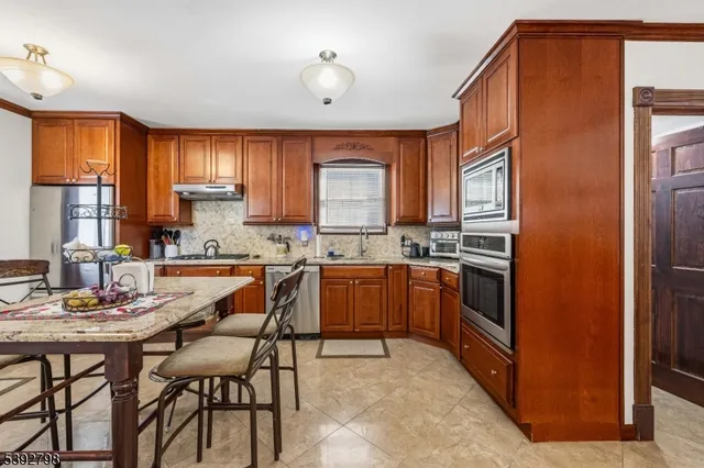 a kitchen with granite countertop a sink cabinets stainless steel appliances and a window