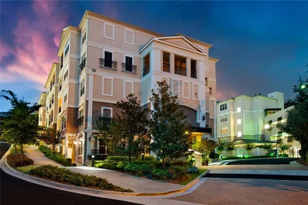 a front view of a multi story residential apartment building with yard and green space