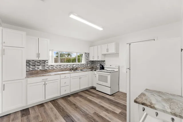 a kitchen with granite countertop white cabinets and white appliances