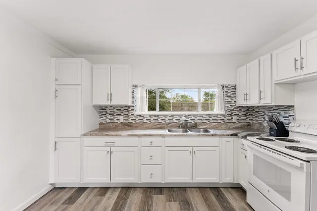a kitchen with granite countertop white cabinets and white appliances
