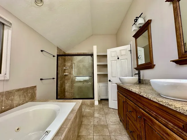 a bathroom with a granite countertop tub sink and mirror