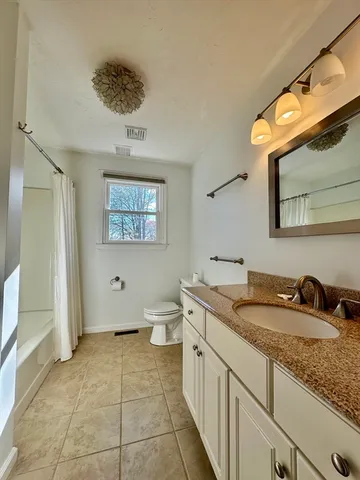 a spacious bathroom with a granite countertop sink a toilet and a mirror