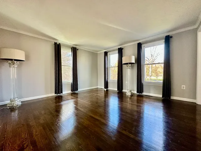 a view of an empty room with window and wooden floor
